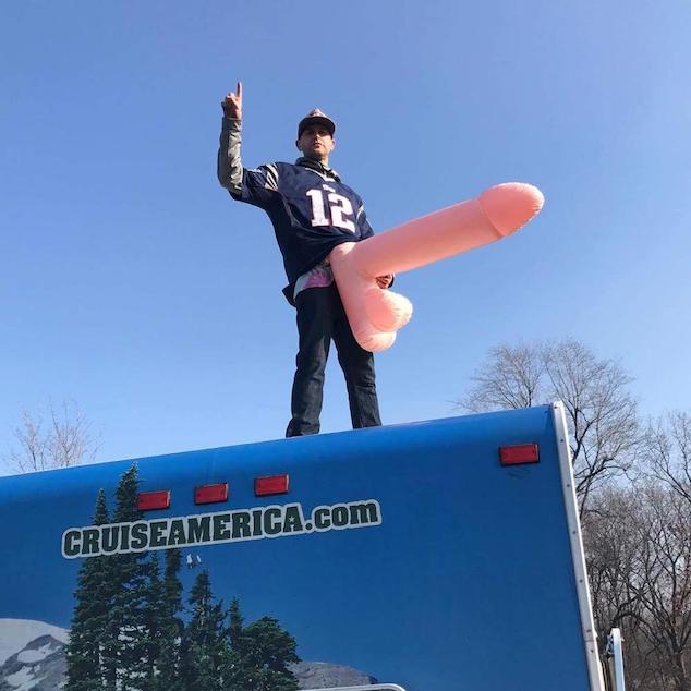 Greg with an inflatable penis on top of an RV
